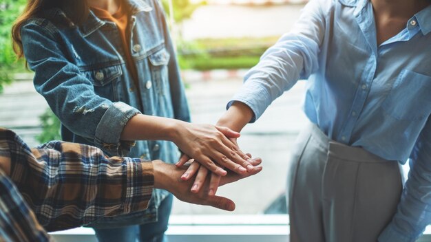 Closeup image of business team standing and joining their hands together in office