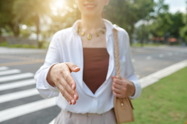 Closeup image of businesswoman outstretching arm for handshake selective focus