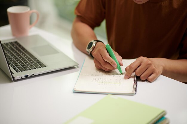 Closeup image of computer science student writing in textbook when doing homework