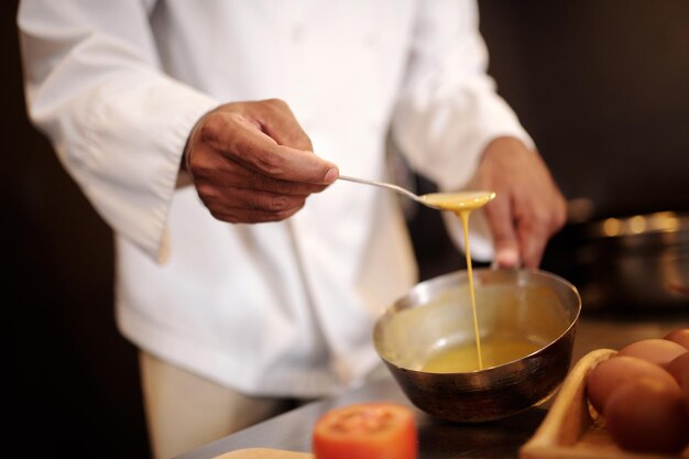 Immagine in primo piano di un cuoco che prepara una deliziosa salsa per la pasta