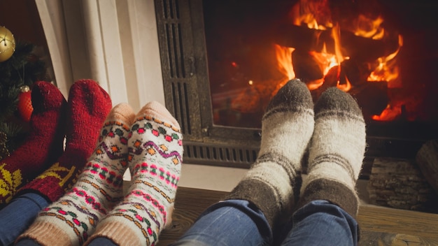 燃える火によって暖まる羊毛の靴下で子供と家族のクローズアップ画像