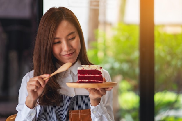 Closeup image of a female chef baking and eating a piece of red velvet cake in wooden tray
