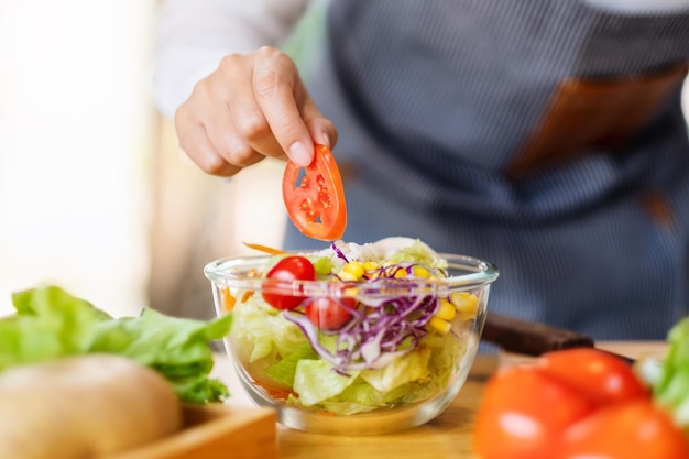 Closeup image of a female chef cooking a fresh mixed vegetables salad in kitchen