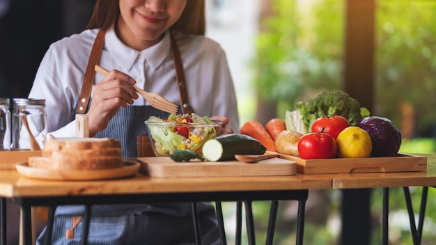 キッチンで新鮮な混合野菜サラダを調理する女性シェフのクローズアップ画像