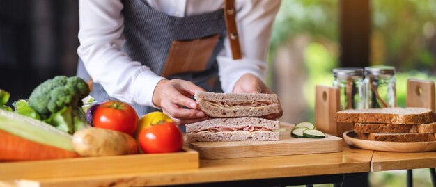 부엌에서 통밀 햄 치즈 샌드위치를 요리하고 들고 있는 여성 요리사의 클로즈업 이미지