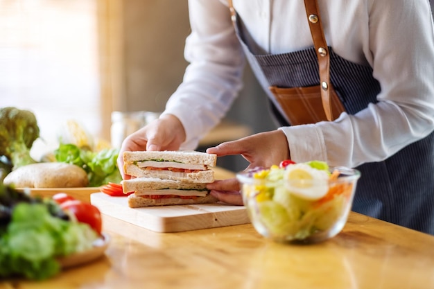 Closeup image of a female chef cooking and holding a piece of whole wheat sandwich in kitchen