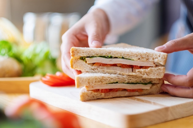 Closeup image of a female chef cooking and holding a piece of whole wheat sandwich in kitchen