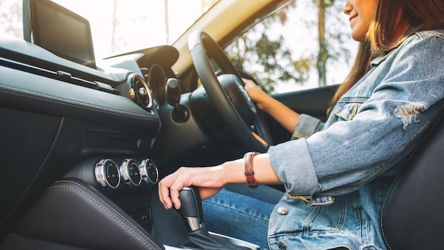 クローズアップ画像車を運転中に自動ギアスティックをシフトする女性ドライバー