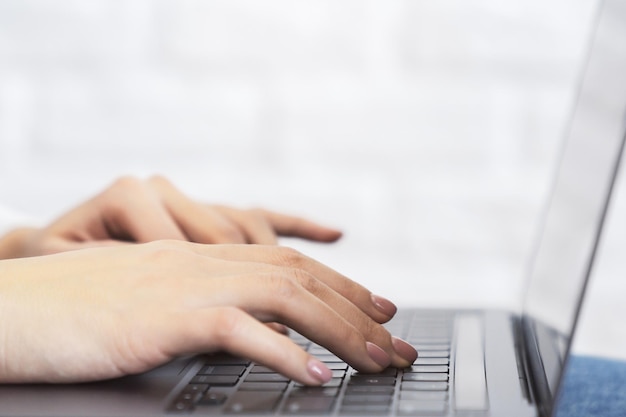 Closeup image of female hands typing on a cuttingedge laptop keyboard with a soft blur of an office setting in the backdrop