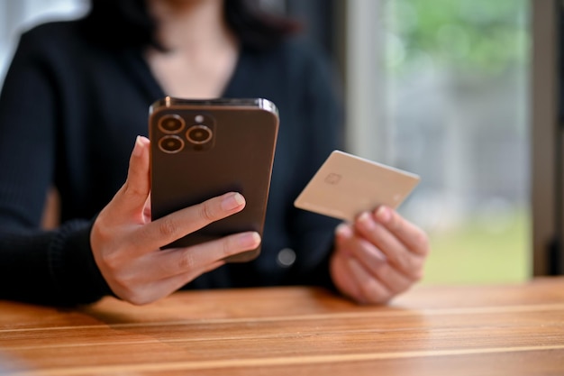 Closeup image of a female holding a credit card and smartphone using her mobile banking