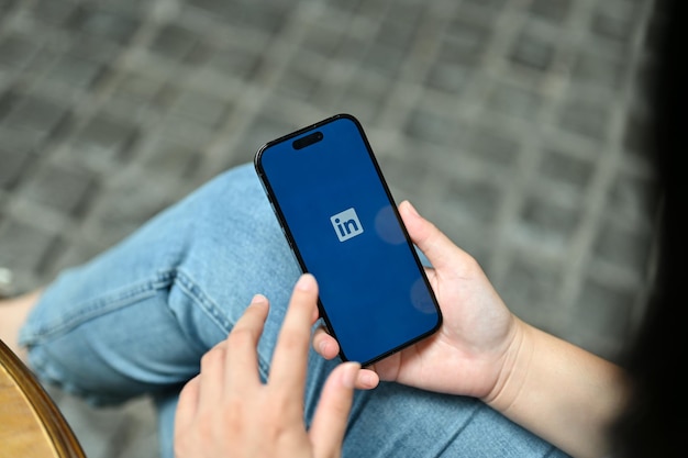 屋外でリラックスしながら LinkedIn アプリケーションを使用している女性のクローズアップ画像