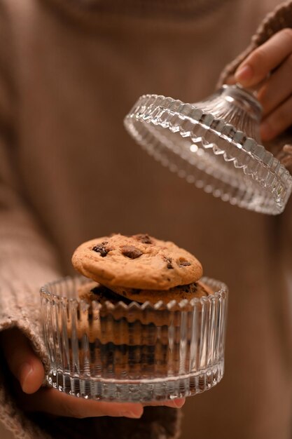 Immagine del primo piano femmina in maglione caldo aprire un barattolo di biscotti biscotti con gocce di cioccolato fatti in casa