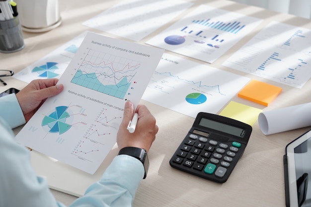 Closeup image of financial analyst examining document with various charts indicating company performance