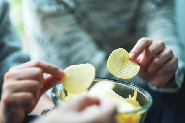 Closeup image of friends sharing and eating potato chips at home party together