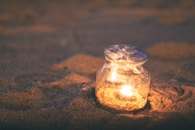 夜のビーチでガラス瓶キャンドルホルダーのクローズアップ画像