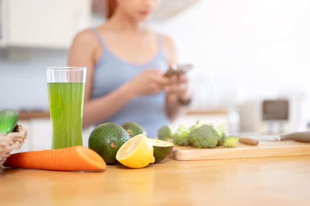 台所のテーブルの上にある健康的な青汁と新鮮な果物と野菜のグラスのクローズアップ画像