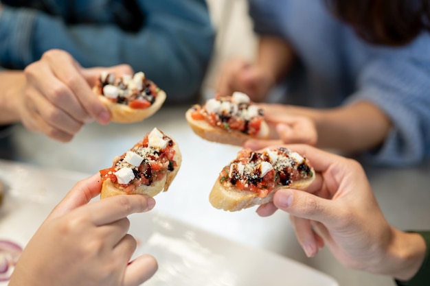 Photo closeup image of a group of friends enjoying eating food at an italian restaurant together