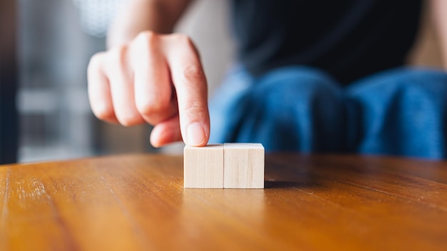 Closeup image of a hand choosing and picking two pieces of blank wooden cube block