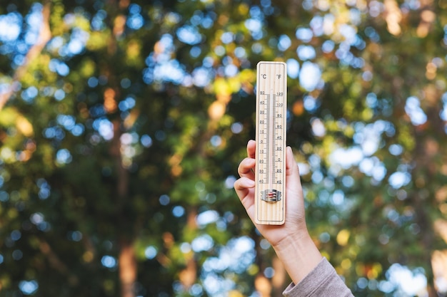 Photo closeup image of a hand holding and showing thermometer in the outdoors