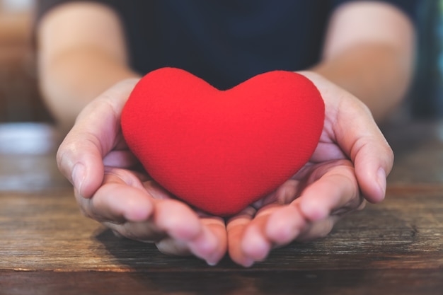 Closeup image of hands holding a red heart sign