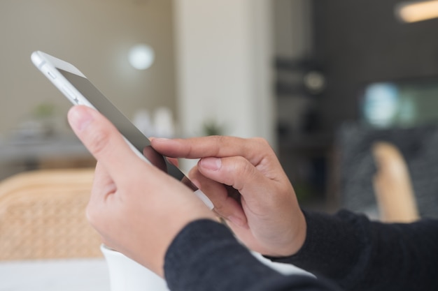 Immagine del primo piano delle mani che tengono, usando e indicando allo smart phone in caffè