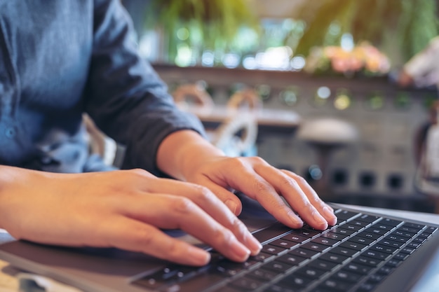 Closeup image of hands using and typing on laptop keyboard in cafe