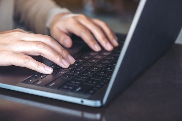 Closeup image of hands using and typing on laptop keyboard on table