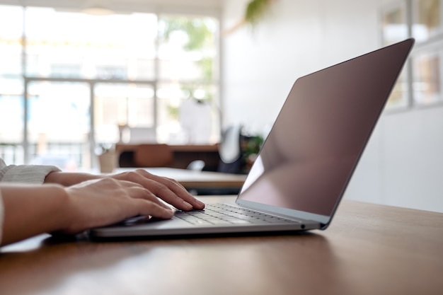 Closeup image of hands using and typing on laptop keyboard on the table