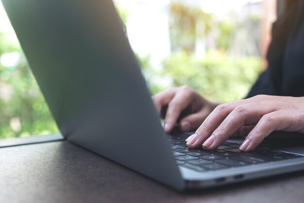 Closeup image of hands working and typing on laptop keyboard in office