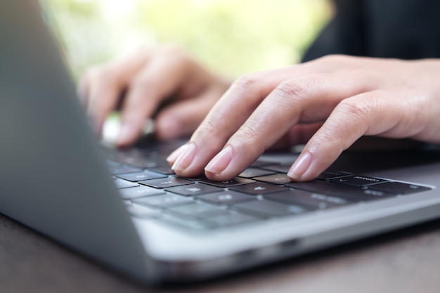 Closeup image of hands working and typing on laptop keyboard in office