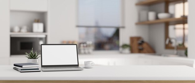 Closeup image of a laptop mockup and copy space on a table in a modern white kitchen