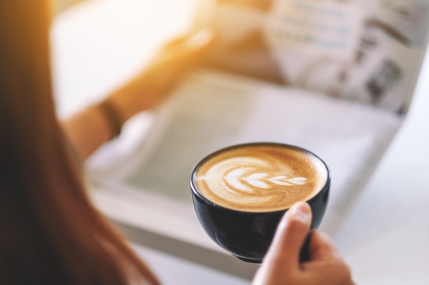 Closeup image of a man reading newspaper and drinking coffee in the morning