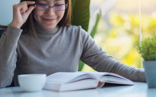 사진 책을 읽고 안경을 쓴 아름다운 젊은 아시아 여성의 클로즈업 이미지