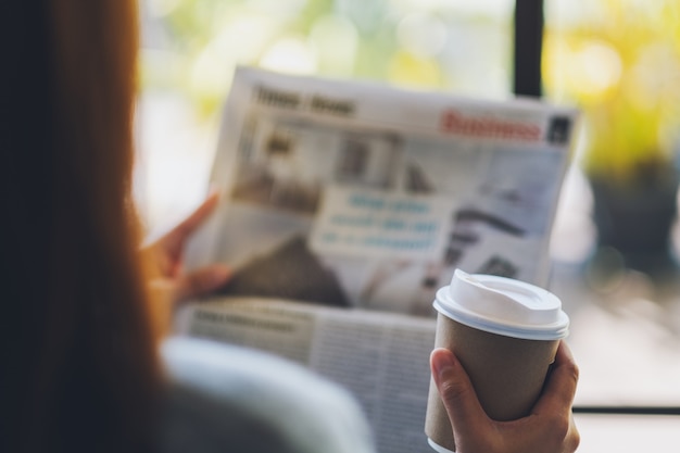 写真 新聞を読んで、朝のコーヒーを飲む女性のクローズアップ画像