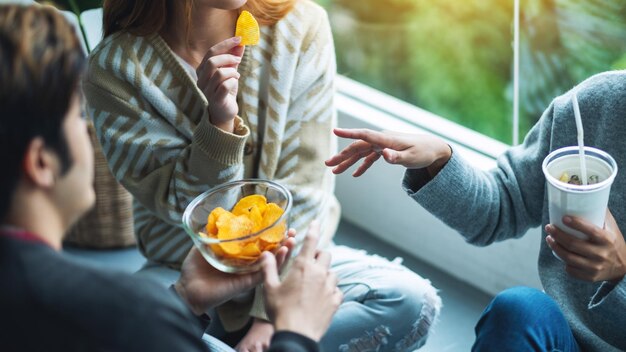 写真 友達が一緒にポテトチップスを飲んで食べているクローズアップ画像