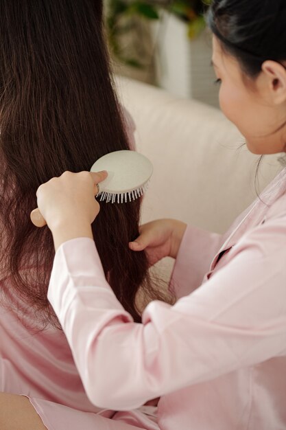 写真 友人や妹に彼女の長いもつれた髪を磨かせている女性のクローズアップ画像