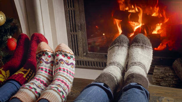 Closeup image of parents with child wearing wool socks relaxing at fireplace