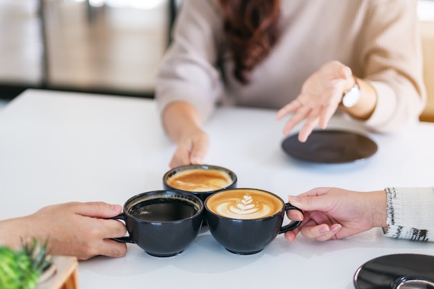 Крупным планом изображение людей, которые пили и звенели кофейными чашками на столе в кафе