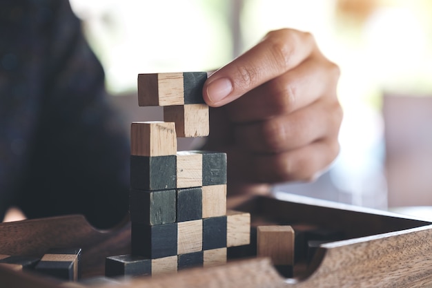 Closeup image of people playing and building wooden puzzle game