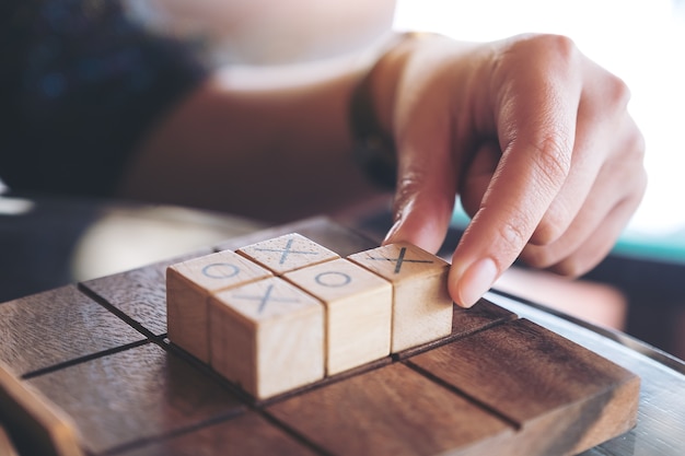 Closeup image of people playing wooden Tic Tac Toe game or OX game 