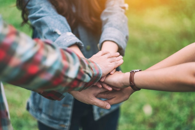 Closeup image of people putting their hands together in the outdoors