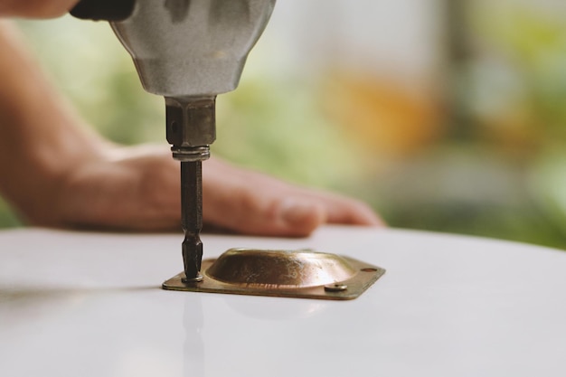 Closeup image of person attaching metal plate to table top to fix legs