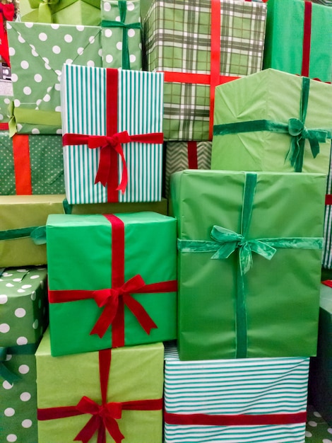 たくさんのクリスマス プレゼントの山のクローズ アップ画像。新年のプレゼントが付いている赤いリボンが付いている緑の箱のスタック