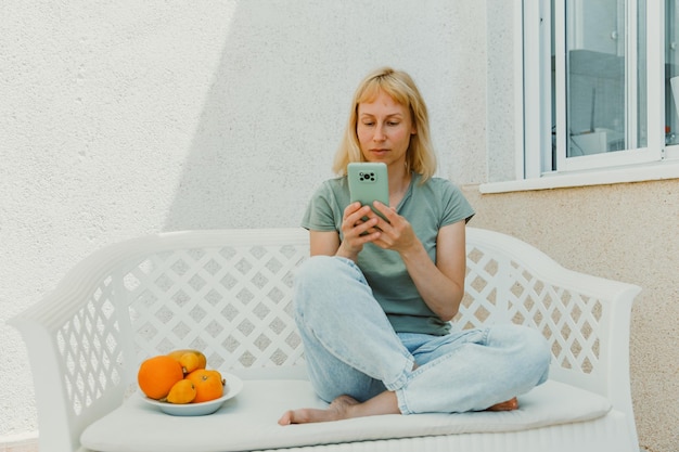 Closeup image of pretty woman sitting at cozy home interior and using modern smartphone device female hands typing text message via cellphone social networking concept