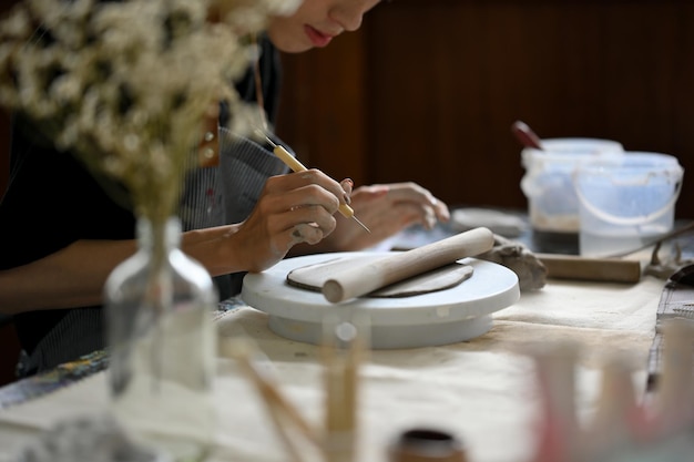 Closeup image of a professional male pottery artist holding a sculpting tool