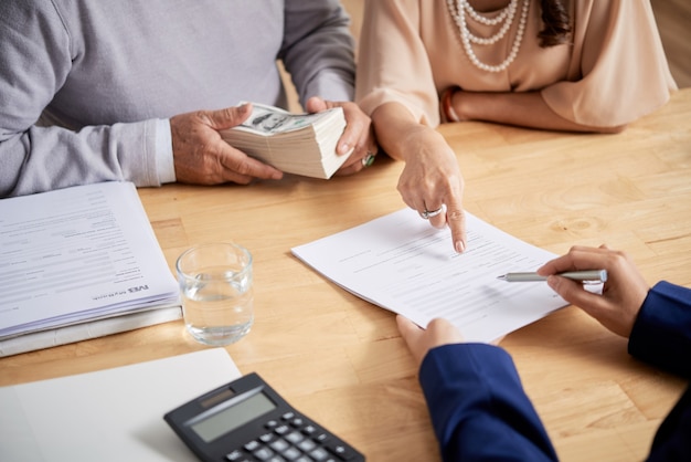 Closeup image of senior couple filling sale deed form and making down payment for new house