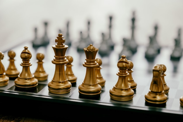 Closeup image of a silver and golden color chess set on chessboard