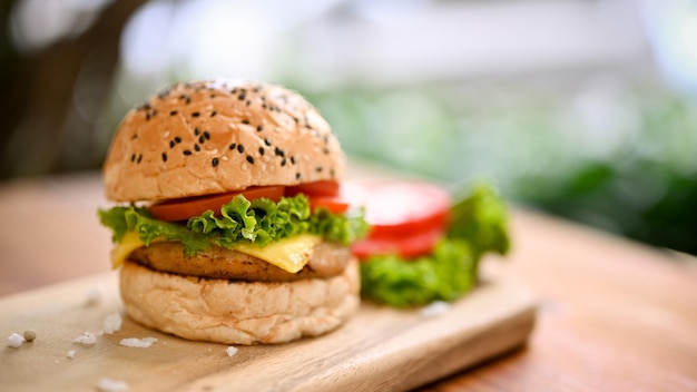 Closeup image of a tasty beef burger with fresh vegetables on wooden tray