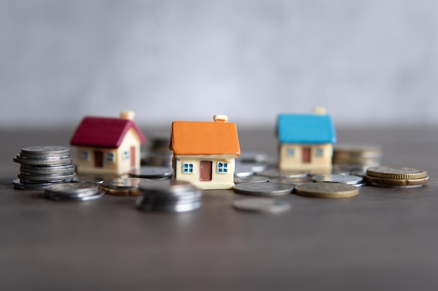 Closeup image of toy house surrounded by coins Copy space for text Home ownership concept