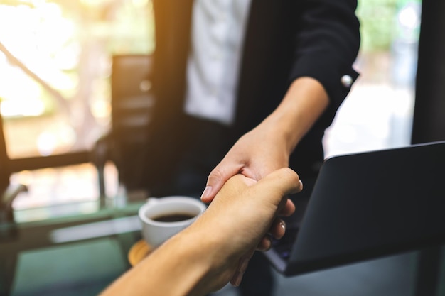 Closeup image of two businesspeople shaking hands in office